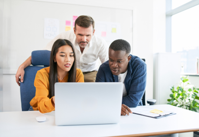 Diverse team collaborating on a laptop, symbolising customer-centred financial regulation and vulnerable customer treatment