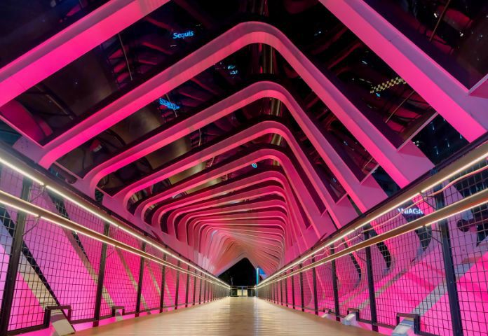 Futuristische Fußgängerbrücke mit leuchtend rosa Beleuchtung, die die digitale Transformation in der Kreditvergabe von Lenvi symbolisiert