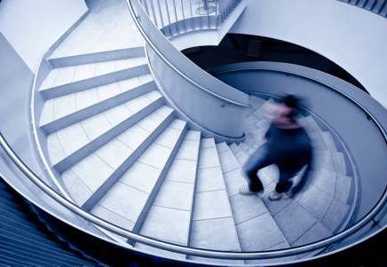 Spiral staircase with a moving figure, symbolising addressing lending compliance challenges