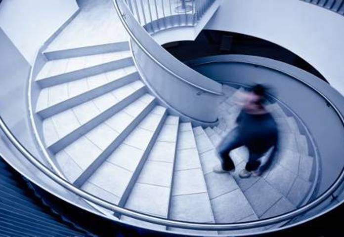 Spiral staircase with a moving figure, symbolising addressing lending compliance challenges
