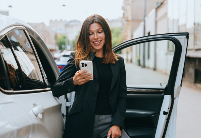 lady using a phone getting out of a car representing Lenvis origination, servicing and loan collections services
