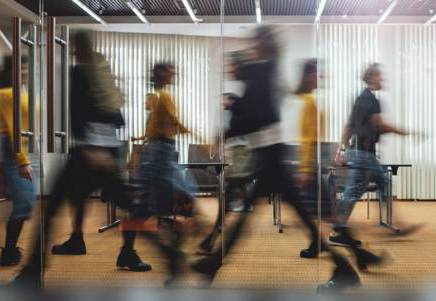 Blurred figures rushing in an office, symbolising lenders embracing Consumer Duty opportunities amidst market change.