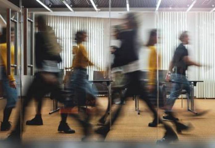 Blurred figures rushing in an office, symbolising lenders embracing Consumer Duty opportunities amidst market change.
