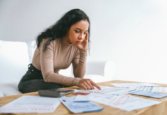 Worried young Gen Z woman reviewing financial documents, symbolising challenges in financial literacy