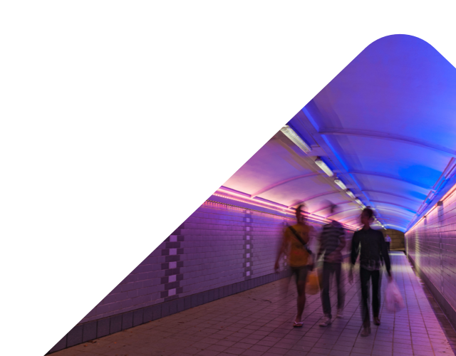 group of people walking in a colourfully lit tunnel - Lenvi