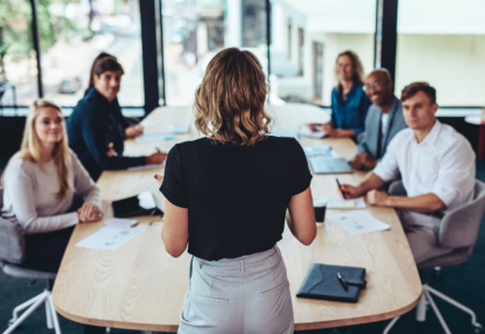 Woman Addressing Board Room Of People