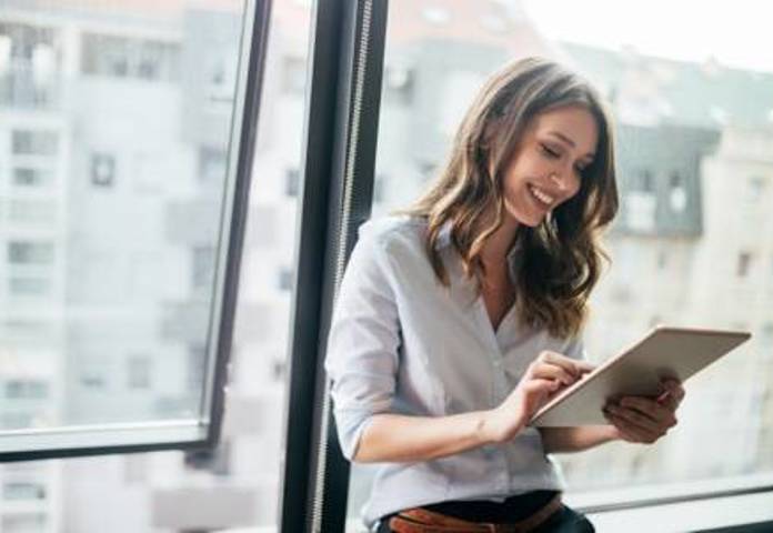 Lenvi - Woman smiling while using a tablet in a modern office, representing digital payment solutions