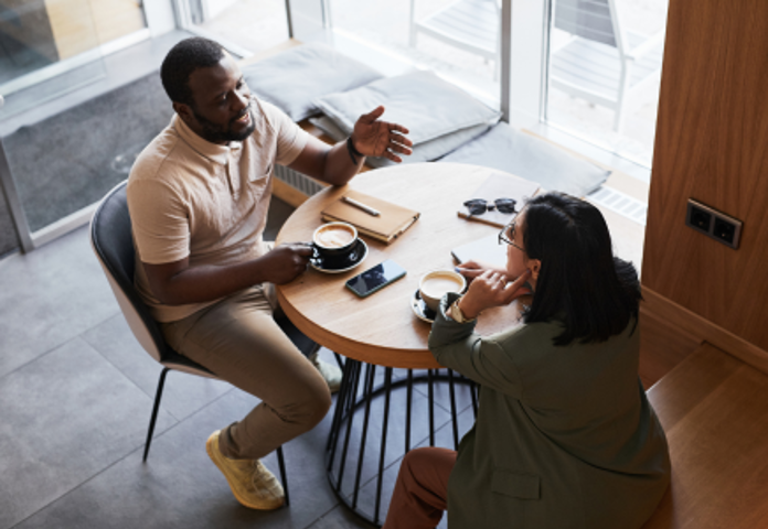 Two people having a serious financial conversation over coffee during Debt Awareness Week Lenvi Debt Awareness Week series
