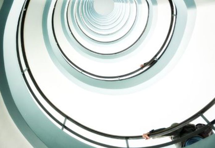 Spiral staircase viewed from below, symbolizing spiralling fraud rates for European business lenders.- Lenvis 2023 fraud readiness report