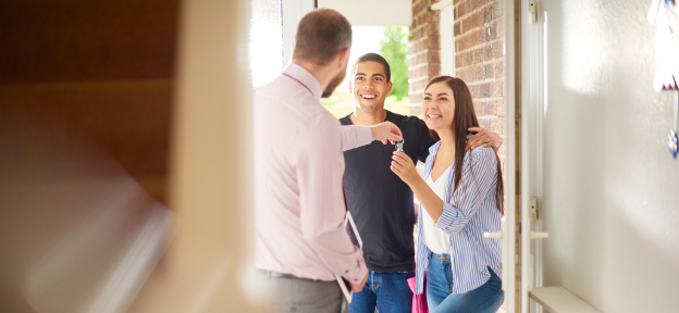 People receiving keys at a property doorway, representing buy-to-let mortgage agreement
