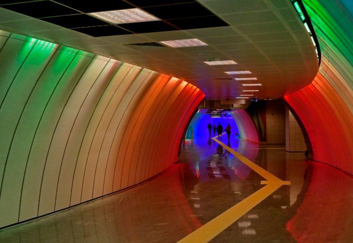 Lenvi image of a multi coloured subway tunnel with figures in background